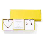 Kendra Scott Cailin Birthstone Gift Set for January in gold with Red Crystal, a pendant necklace and huggie earrings in a yellow gift box