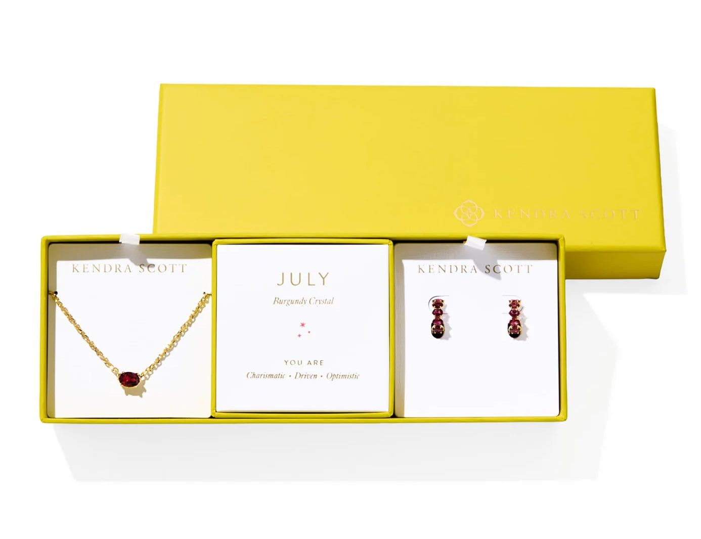 Kendra Scott Cailin Birthstone Gift Set for July in gold with Burgundy Crystal, a pendant necklace and huggie earrings in a yellow gift box