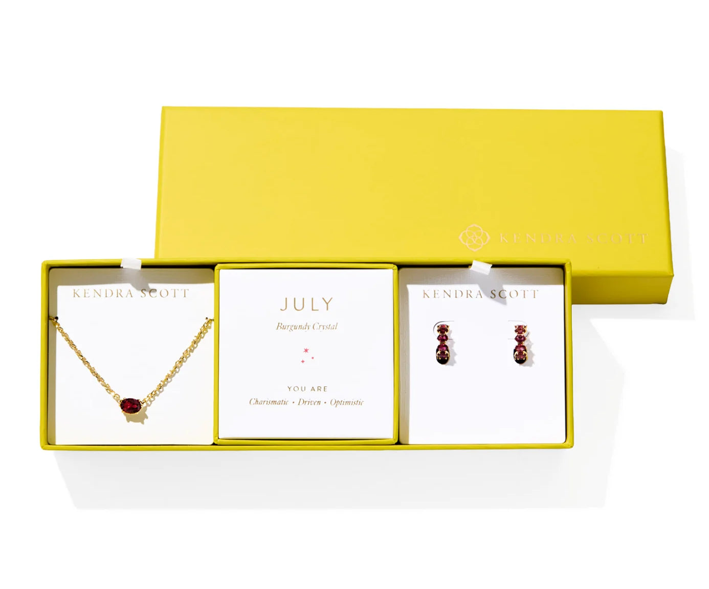 Kendra Scott Cailin Birthstone Gift Set for July in gold with Burgundy Crystal, a pendant necklace and huggie earrings in a yellow gift box