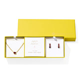 Kendra Scott Cailin Birthstone Gift Set for July in gold with Burgundy Crystal, a pendant necklace and huggie earrings in a yellow gift box