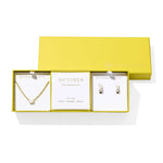 Kendra Scott Cailin Birthstone Gift Set for October in gold with White Iridescent Crystal, a pendant necklace and huggie earrings in a yellow gift box