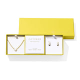 Kendra Scott Cailin Birthstone Gift Set for October in gold with White Iridescent Crystal, a pendant necklace and huggie earrings in a yellow gift box