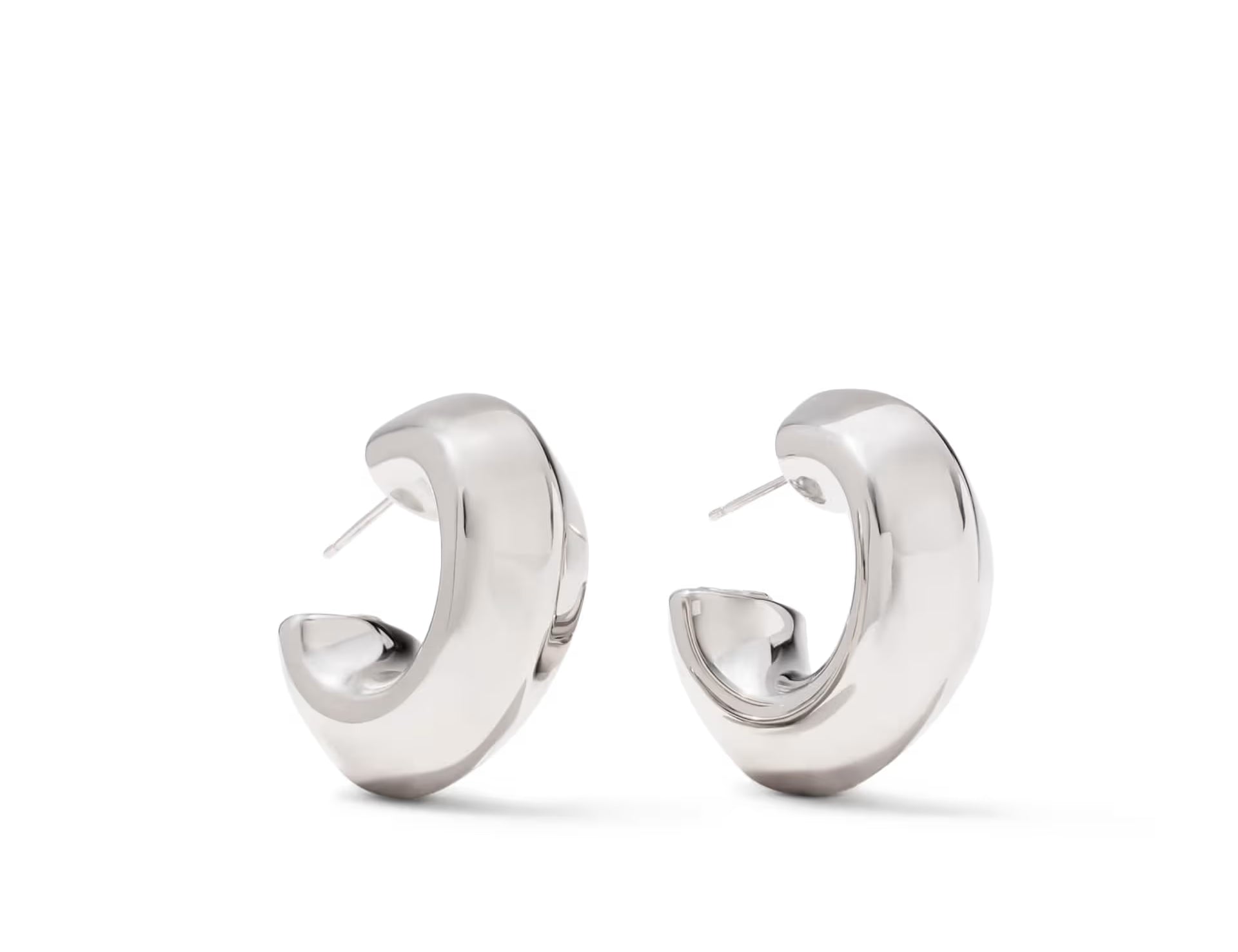 A pair of polished silver huggie hoop earrings with a curved, modern design, displayed on a clean white background.