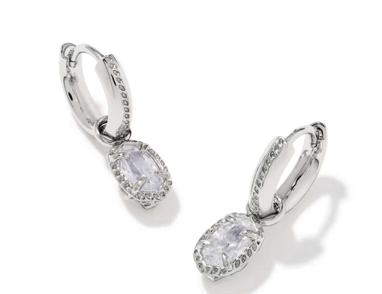 Kendra Scott Mini Ellie Luxe Huggie Earrings in Silver with oval white crystal drops and pave hoops, angled on white