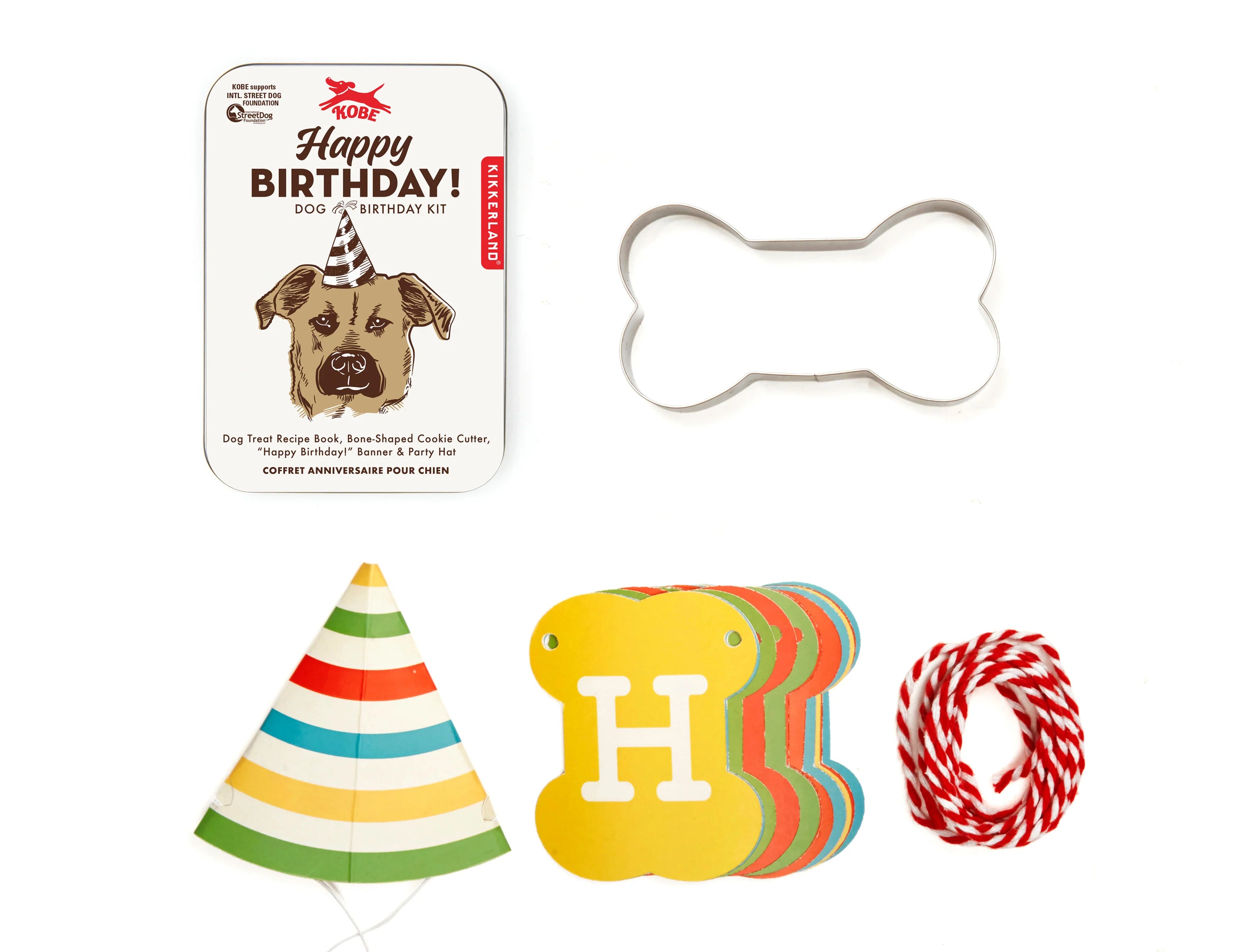 Kikkerland Dog Birthday Kit contents laid out: tin, bone cookie cutter, party hat, Happy Birthday banner and twine