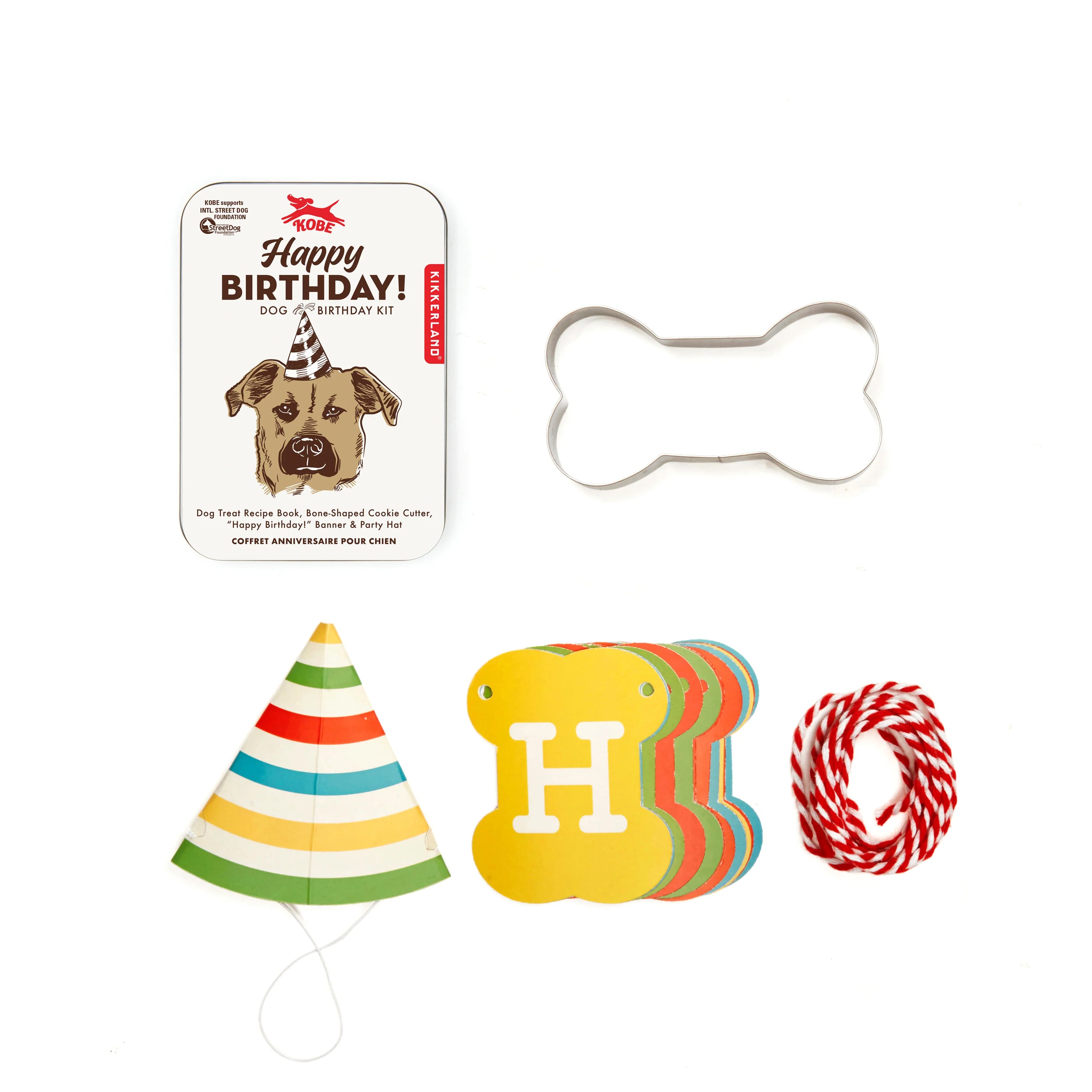 Kikkerland Dog Birthday Kit contents laid out: tin, bone cookie cutter, party hat, Happy Birthday banner and twine