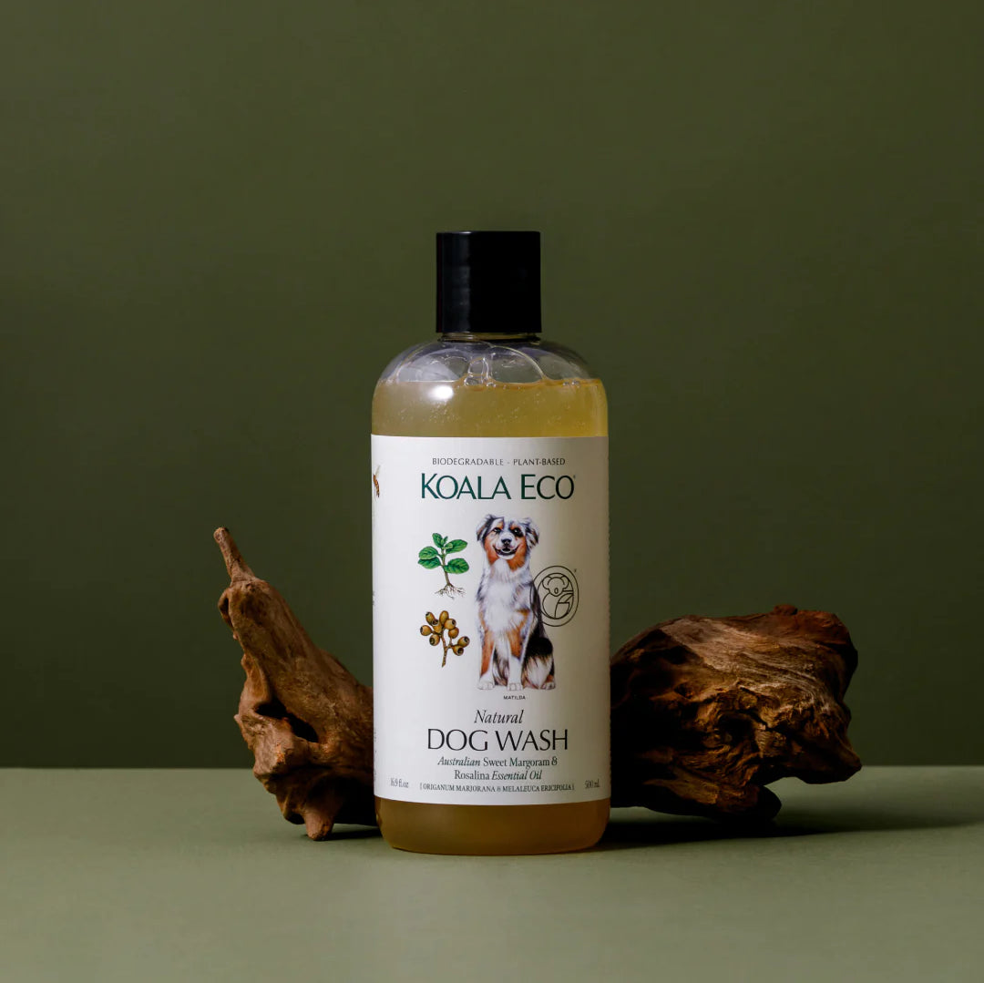 Koala Eco Natural Dog Wash bottle beside a piece of driftwood on a green background