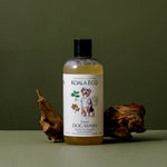 Koala Eco Natural Dog Wash bottle beside a piece of driftwood on a green background