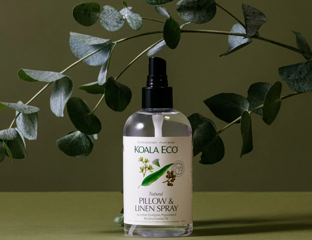 Koala Eco Natural Pillow & Linen Spray bottle under eucalyptus branches on a green background