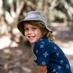 Boy wearing the Kooringal Dozer Boys Bucket Hat in Camo outdoors under trees