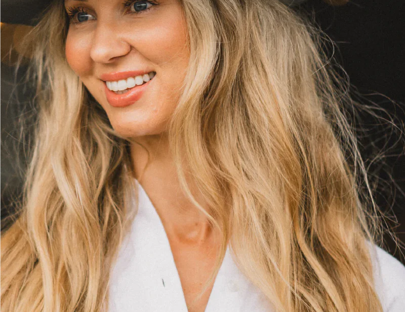 Smiling woman with long blonde hair wearing the Kooringal Goodwin Wide Brim Fedora in Driftwood