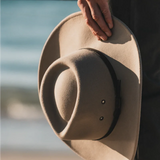 Hand holding the Kooringal Nomad Cowboy Hat in Sand with the brim in soft light