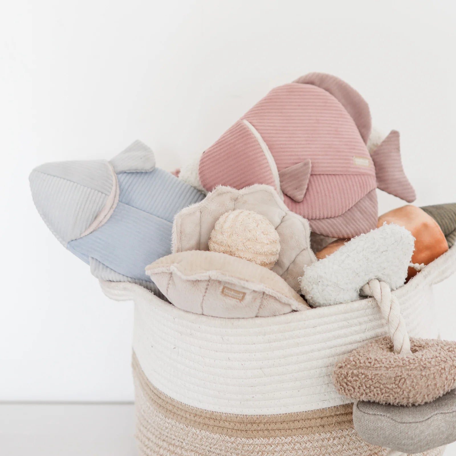 Lambwolf Collective Angel Fish Dog Toys in pink and light blue in a rope basket with other plush toys