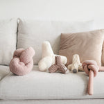 Lambwolf Collective Nounou Dogwood Squeakers Dog Toys in blush and cream on a gray couch