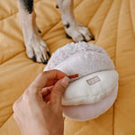 Hand tucking a treat into the Lambwolf Collective Toto Enrichment Dog Toy in Pink
