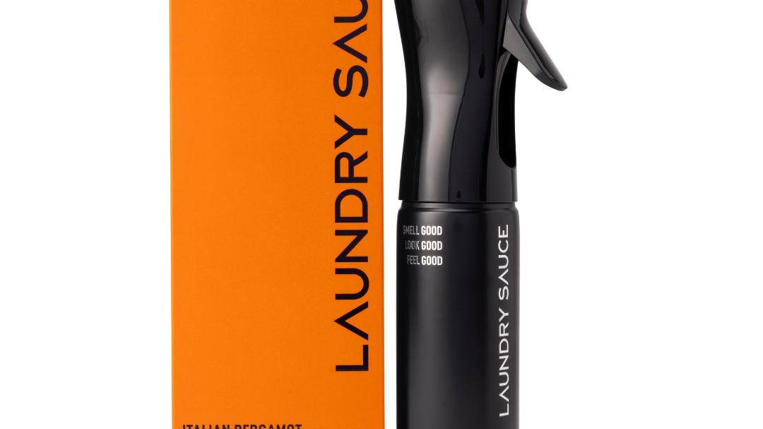 Laundry Sauce Fabric Refresher Spray in Italian Bergamot, a black spray bottle beside its orange box