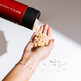 Hand pouring peach Laundry Sauce Laundry Scent Booster beads from a red canister