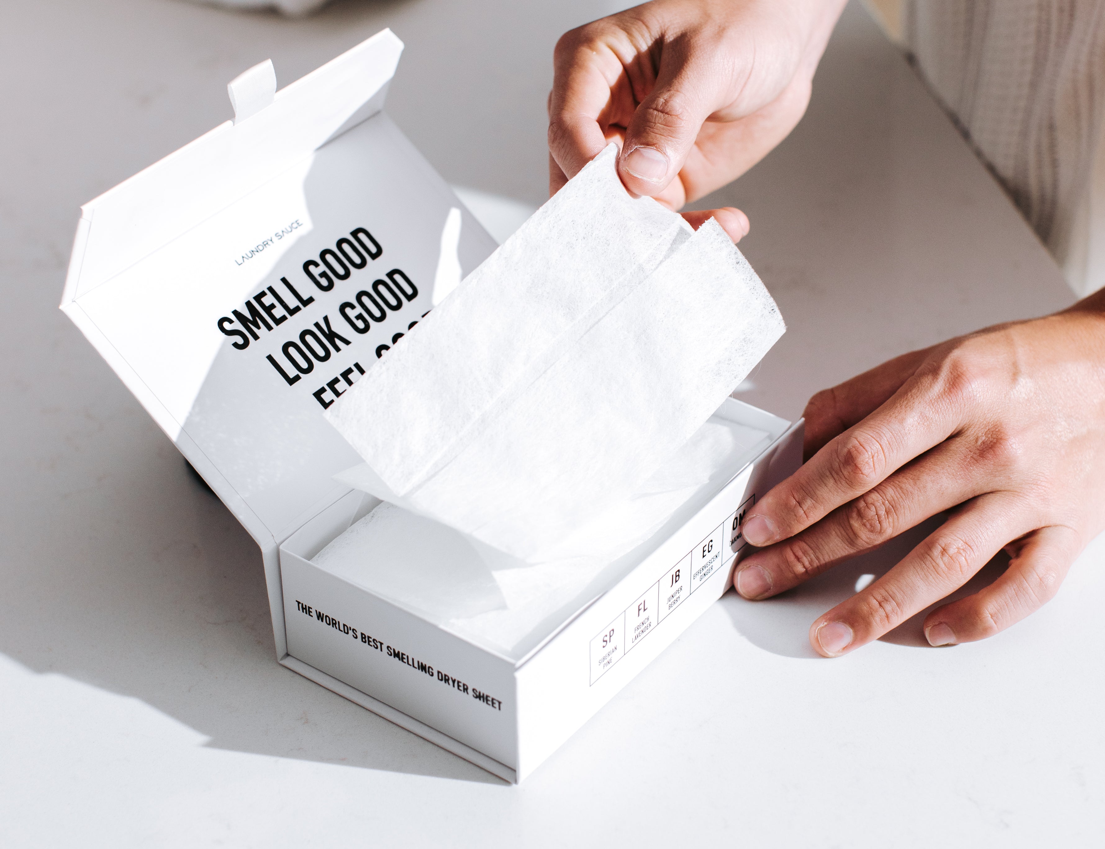 Hands pulling a sheet from a box of Laundry Sauce Luxury Scented Dryer Sheets