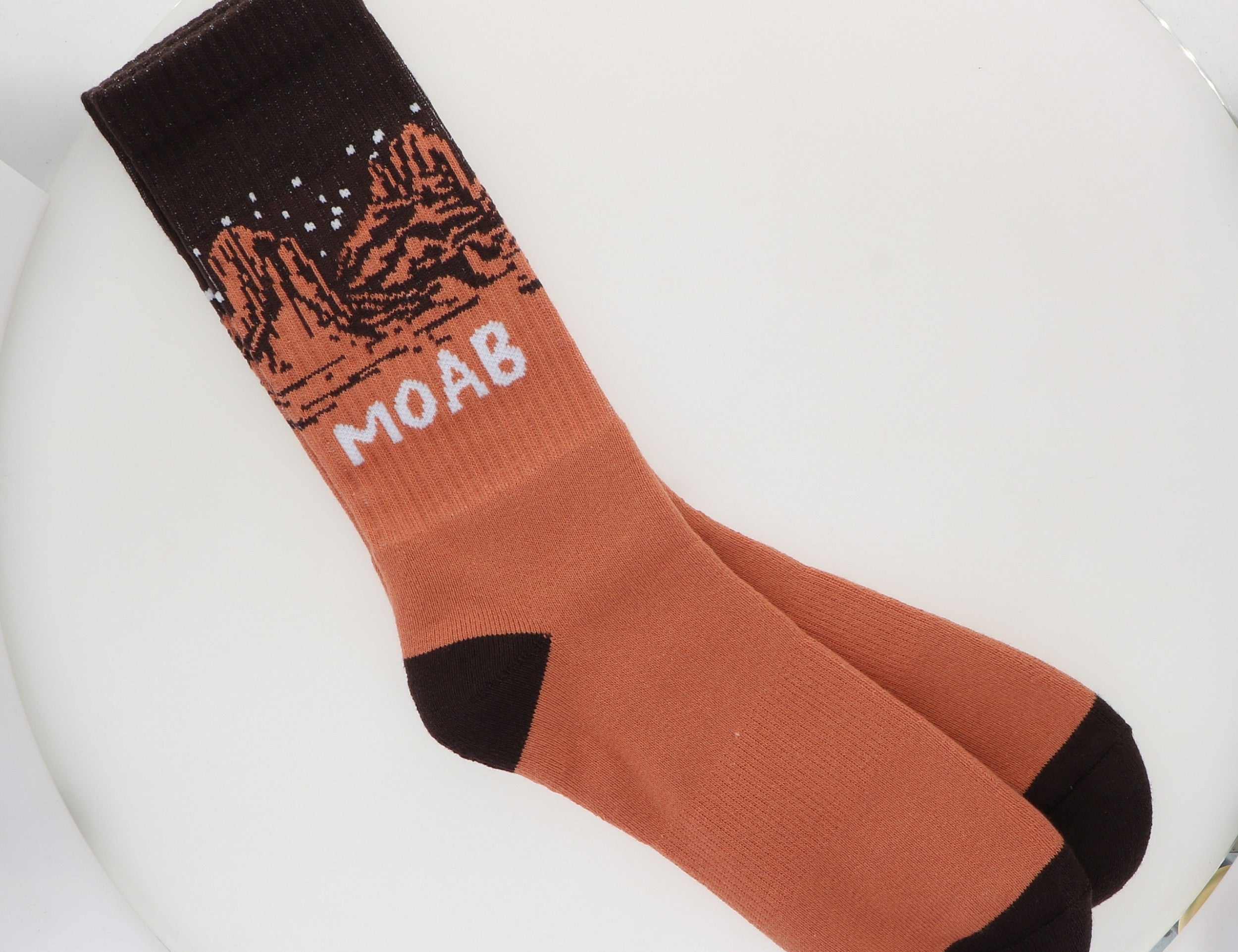 Locale Desert Night Sky Socks, rust orange crew socks with a black starry-sky cuff reading Moab