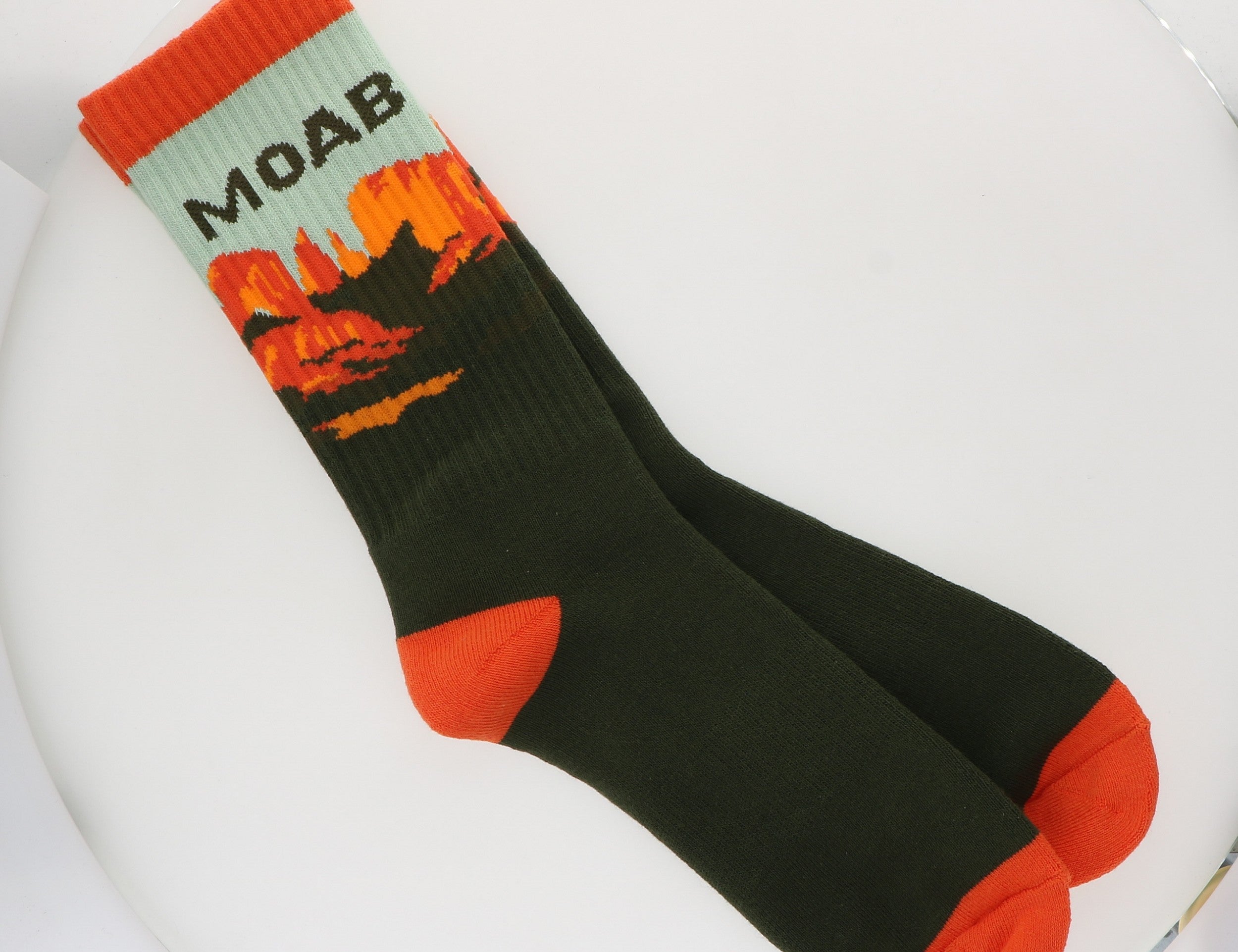 Locale Moab Red Rock Socks, black crew socks with red toes and a red rock landscape cuff reading Moab