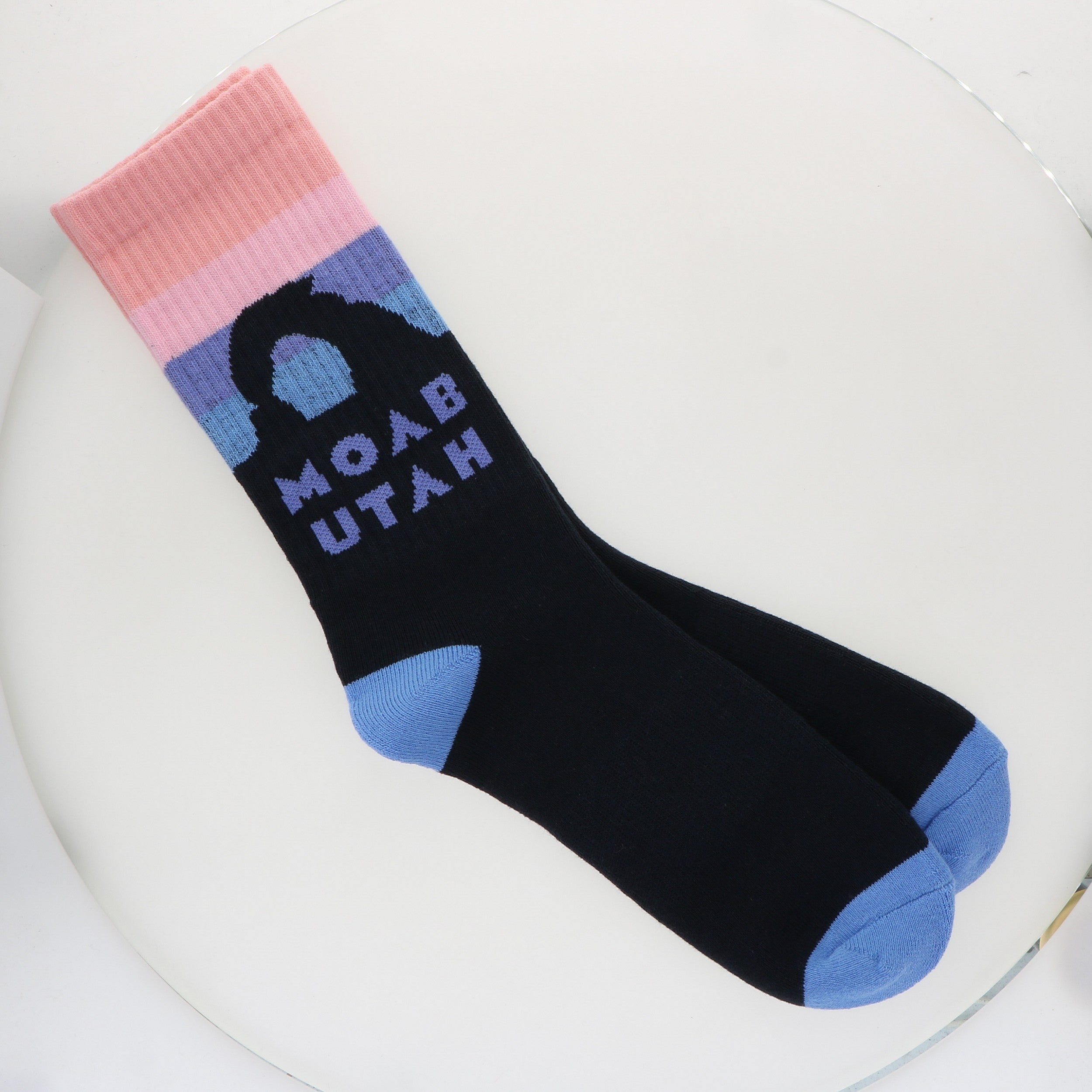 Locale Soft Sunset Moab Socks, black crew socks with a pink and blue sunset and an arch reading Moab Utah