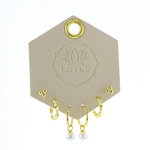 Lotus Studio Gold Trio Earrings in Audrey, dot studs, pave huggies and pearl drop hoops on a Lotus card