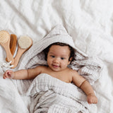 Lou Lou & Company Baby Hair Brush Set, a smiling baby in a hooded towel next to the wooden brushes