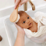 Lou Lou & Company Baby Hair Brush Set, a baby wrapped in a towel being brushed at the sink