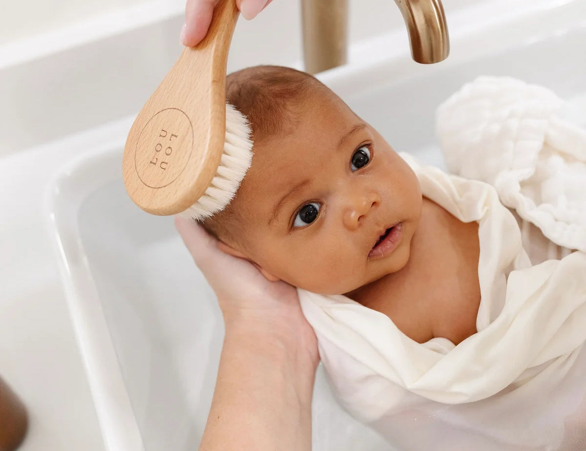 Lou Lou & Company Baby Hair Brush Set, a baby wrapped in a towel being brushed at the sink