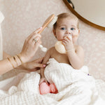 Lou Lou & Company Baby Hair Brush Set, a baby in a white towel having their hair brushed with the wooden brush