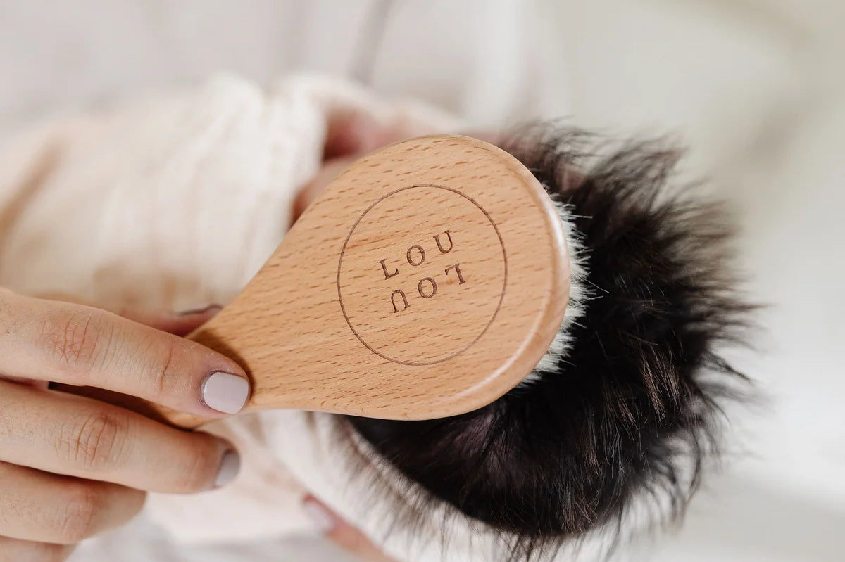 Lou Lou & Company Baby Hair Brush Set, close-up of the engraved Lou Lou wooden brush on a baby's dark hair