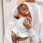 Lou Lou & Company Baby Hair Brush Set, a newborn in a white blanket being brushed in a crib