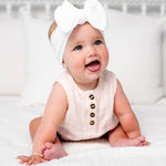 Laughing baby in a blush romper wearing the Lou Lou & Company Cable Knit Headband in Crystal White