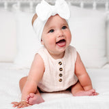 Laughing baby in a blush romper wearing the Lou Lou & Company Cable Knit Headband in Crystal White