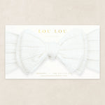 Lou Lou & Company Cable Knit Headband in Crystal White, a soft white bow headband on its card