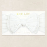 Lou Lou & Company Cable Knit Headband in Crystal White, a soft white bow headband on its card