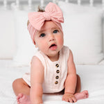 Baby in a blush romper wearing the Lou Lou & Company Cable Knit Headband in Rose