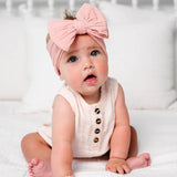 Baby in a blush romper wearing the Lou Lou & Company Cable Knit Headband in Rose