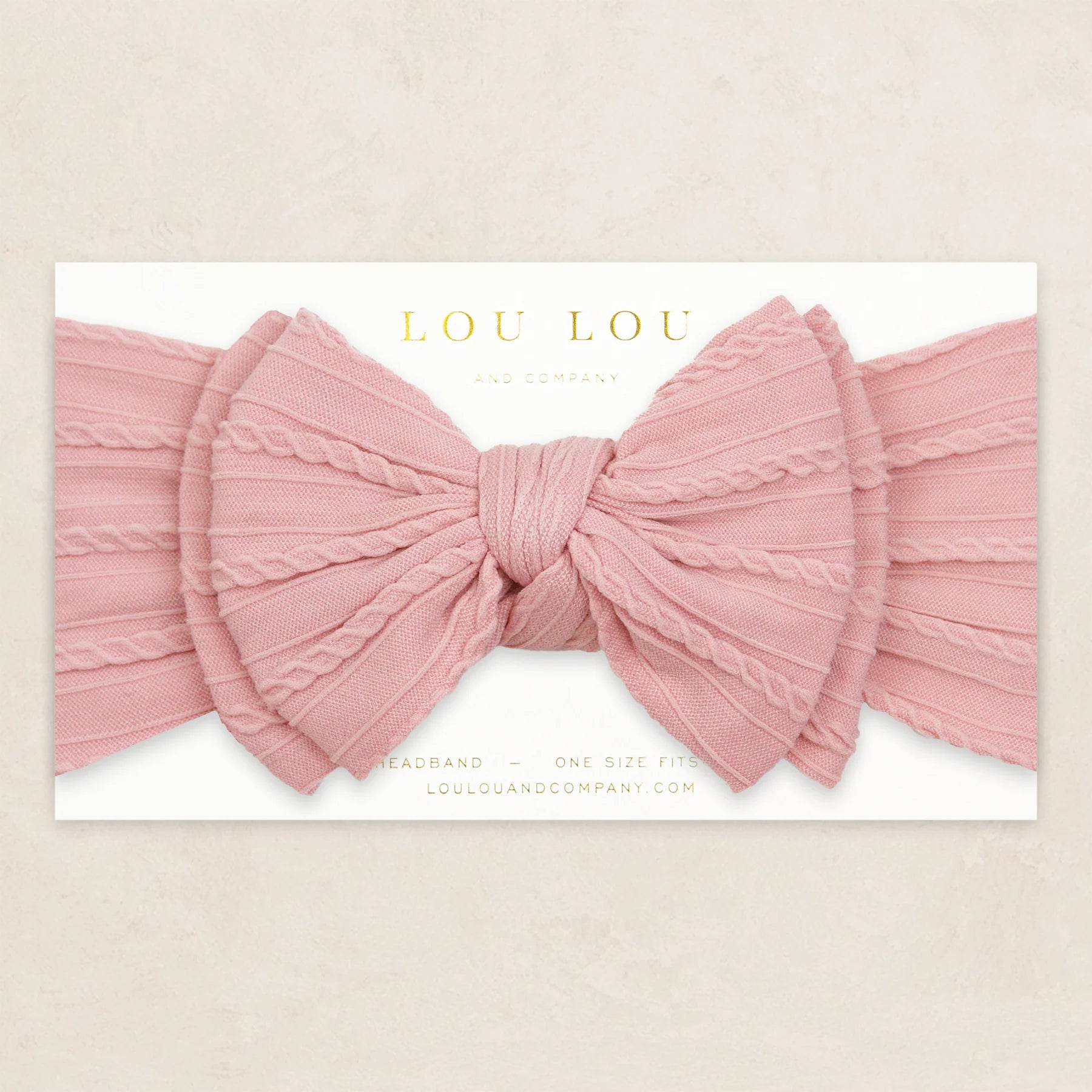 Lou Lou & Company Cable Knit Headband in Rose, a dusty pink bow headband on its card