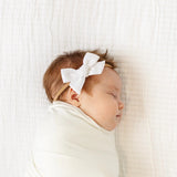 Sleeping newborn swaddled in white wearing the Lou Lou & Company Classic Bow in White