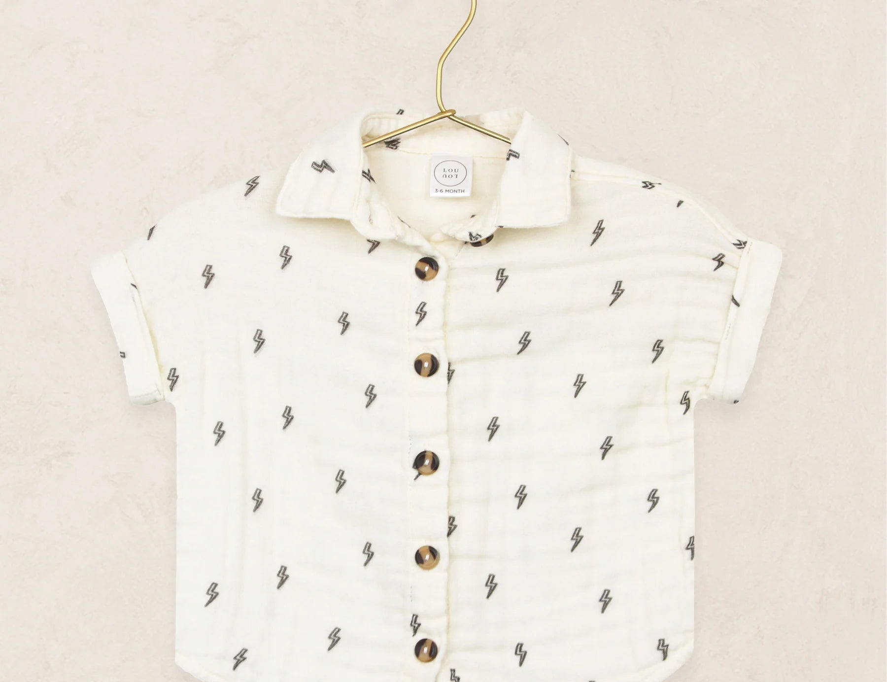 Lou Lou & Company Cloud Muslin Shirt in Lightning Bolt, a cream button-front shirt with a tiny bolt print on a hanger