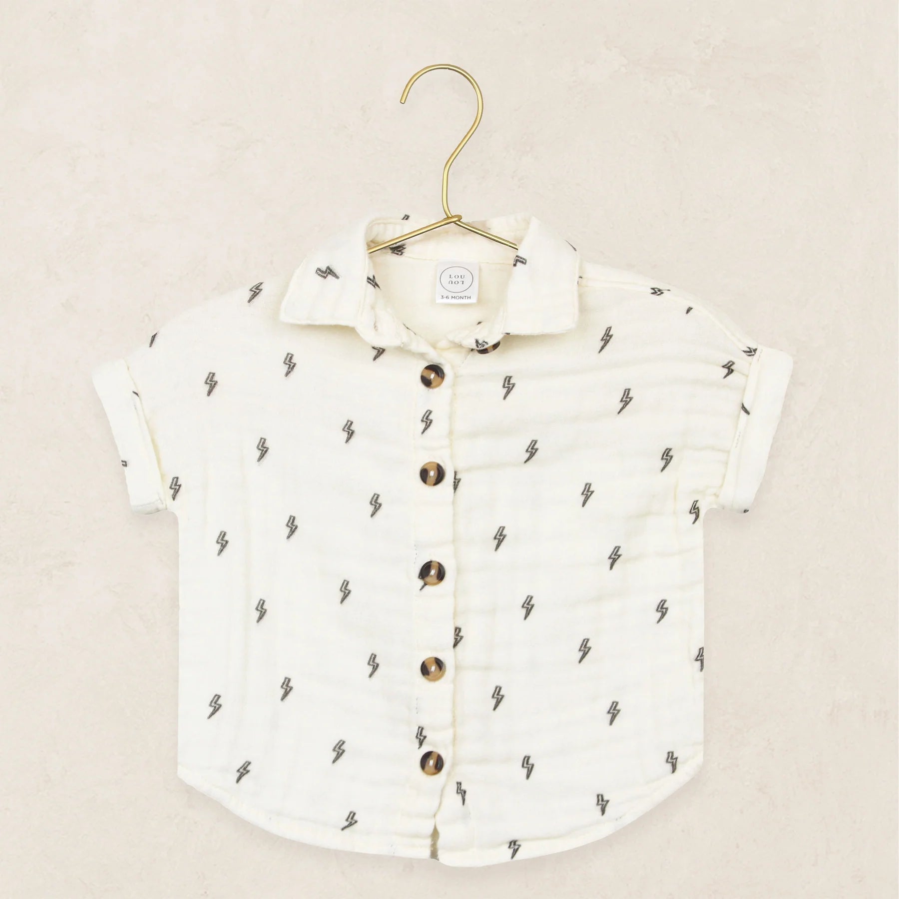 Lou Lou & Company Cloud Muslin Shirt in Lightning Bolt, a cream button-front shirt with a tiny bolt print on a hanger