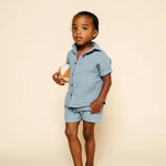 Toddler holding a ball wearing the Lou Lou & Company Cloud Muslin Shirt and Shorts in Steel