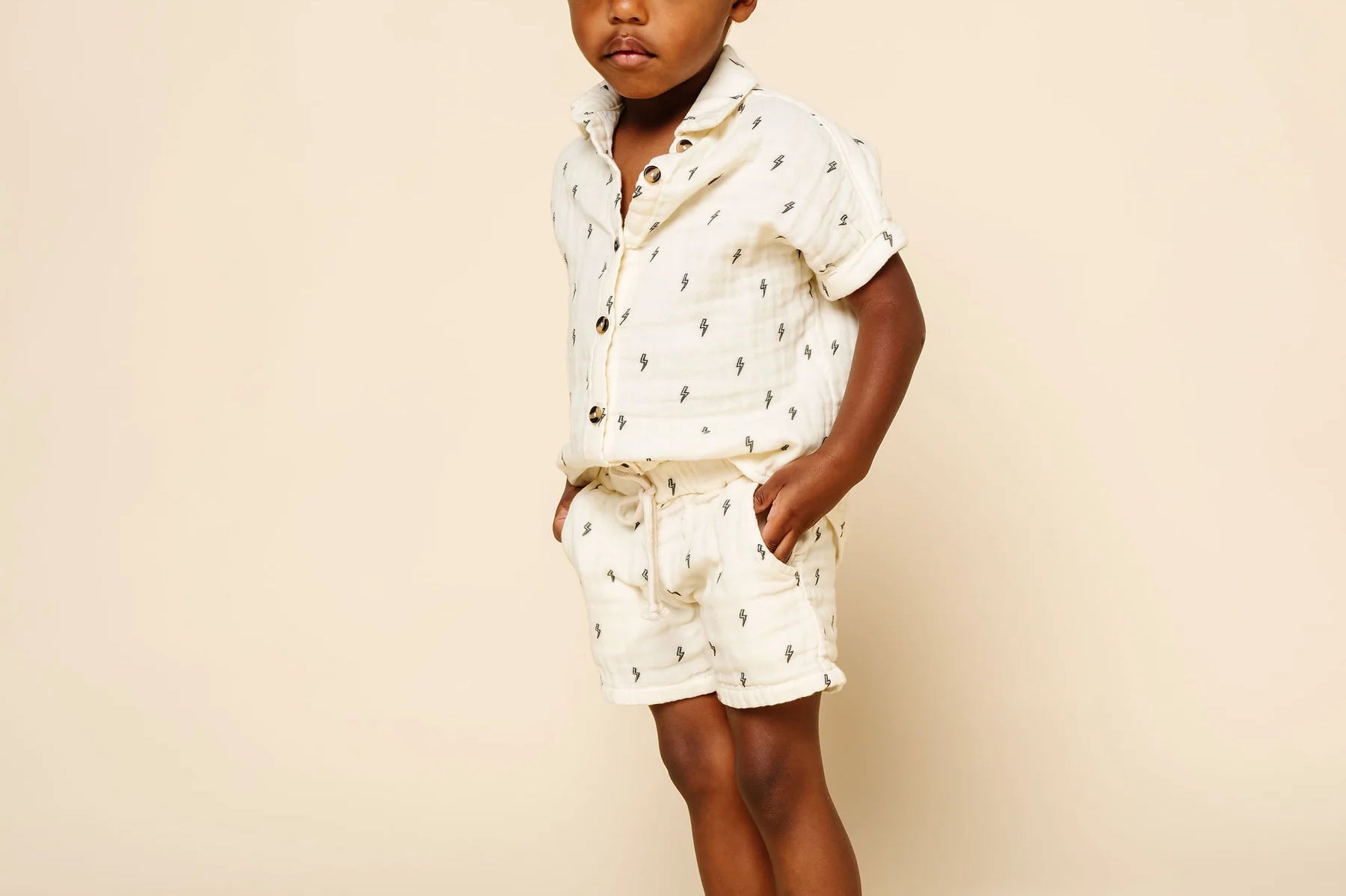 Toddler with hands in pockets wearing the Lou Lou & Company Cloud Muslin Shorts and Shirt in Lightning Bolt