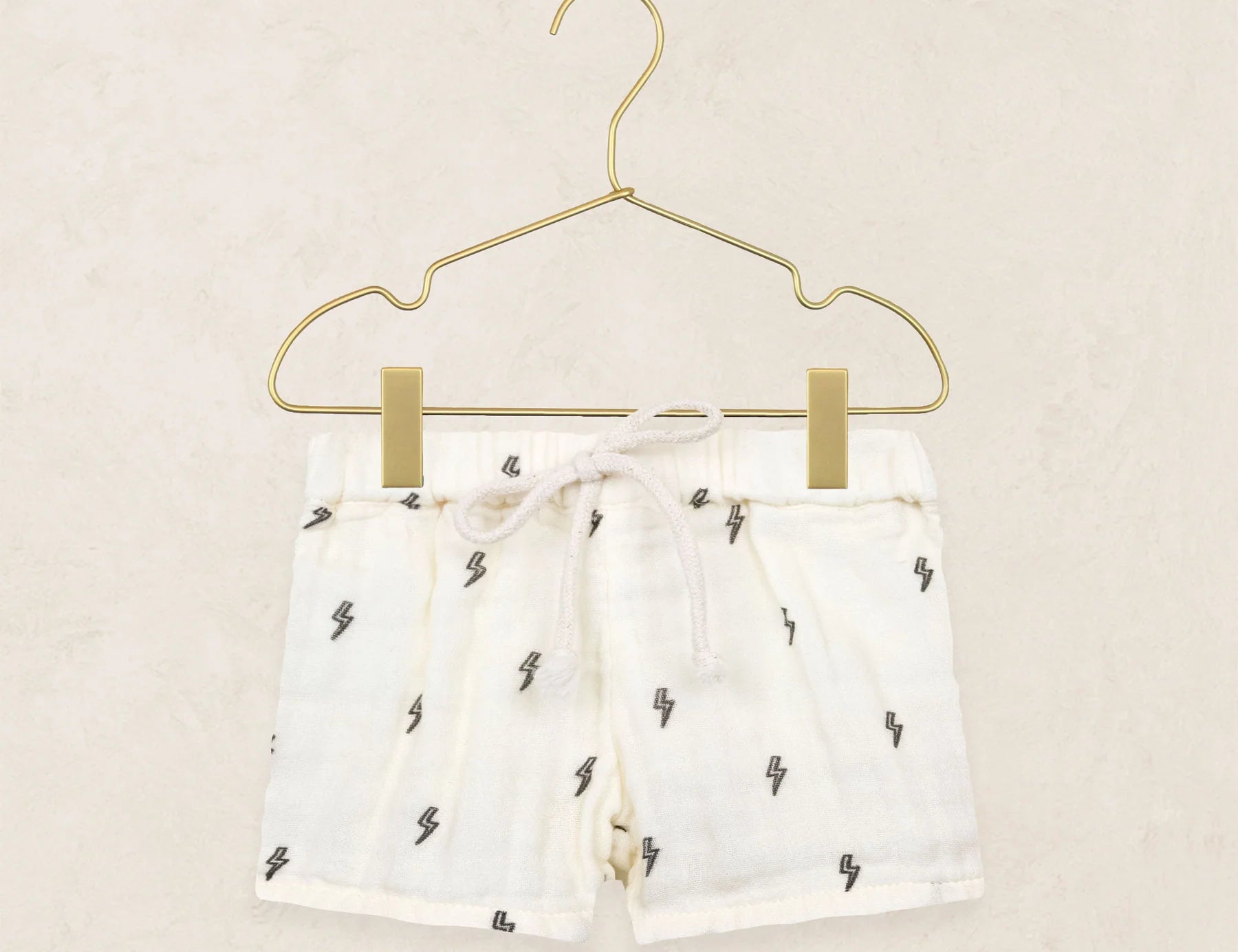 Lou Lou & Company Cloud Muslin Shorts in Lightning Bolt, cream drawstring shorts with a tiny bolt print on a hanger