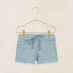 Lou Lou & Company Cloud Muslin Shorts in Steel, soft blue drawstring shorts on a hanger