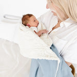 Mother holding a newborn wrapped in the Lou Lou & Company Cozy Blanket in Steel blue, sherpa side out
