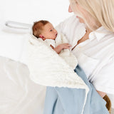 Mother holding a newborn wrapped in the Lou Lou & Company Cozy Blanket in Steel blue, sherpa side out