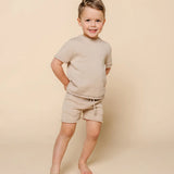 Smiling toddler boy wearing the Lou Lou & Company Knit Tee and Shorts in Tan