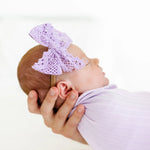 Newborn swaddled in lavender wearing the Lou Lou & Company Lace Bow Headband in Lavender